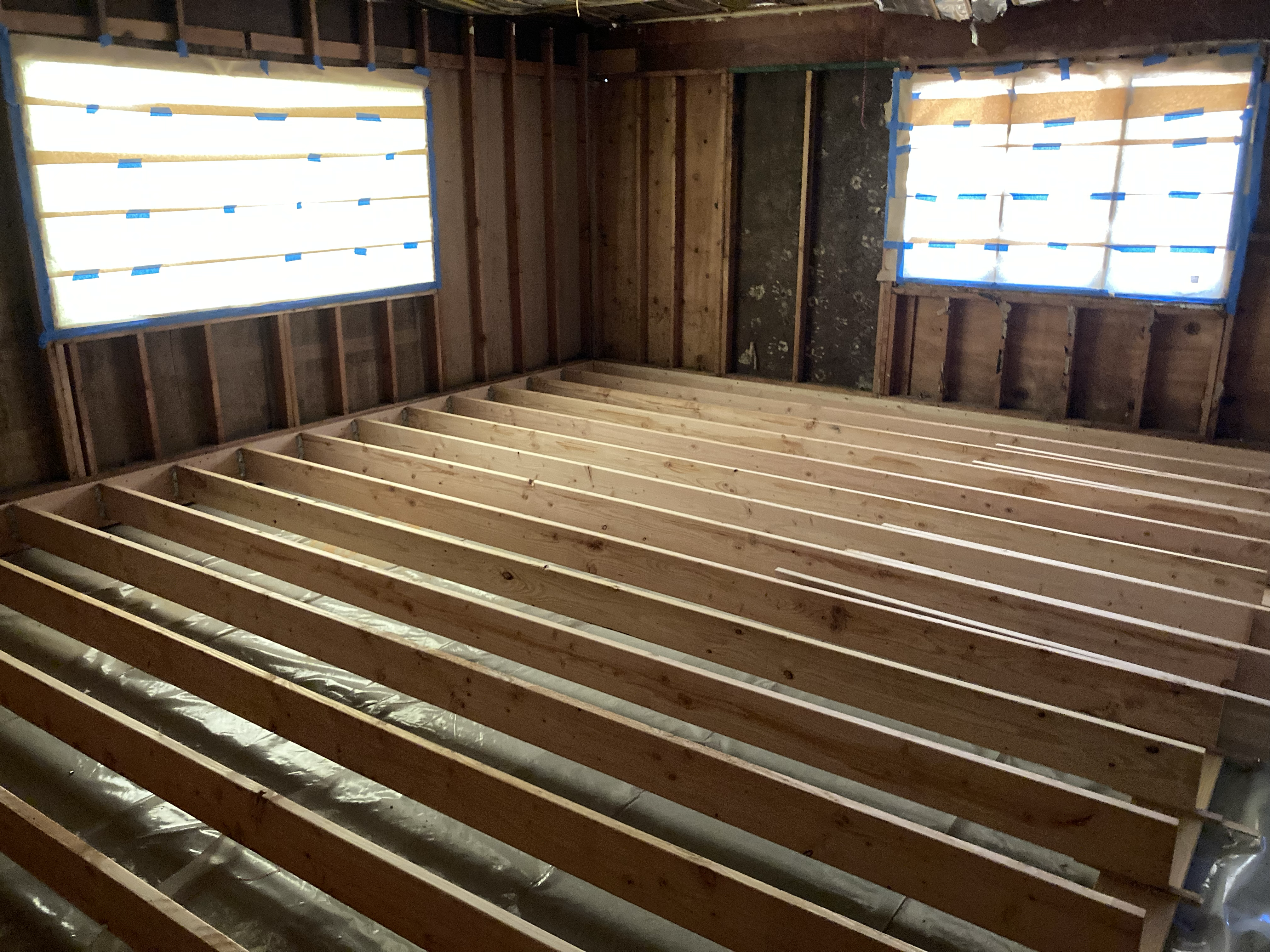 3017 Galvin Road garage, mid-conversion — raised subfloor of beams and sleepers over the slab, vapor barrier beneath