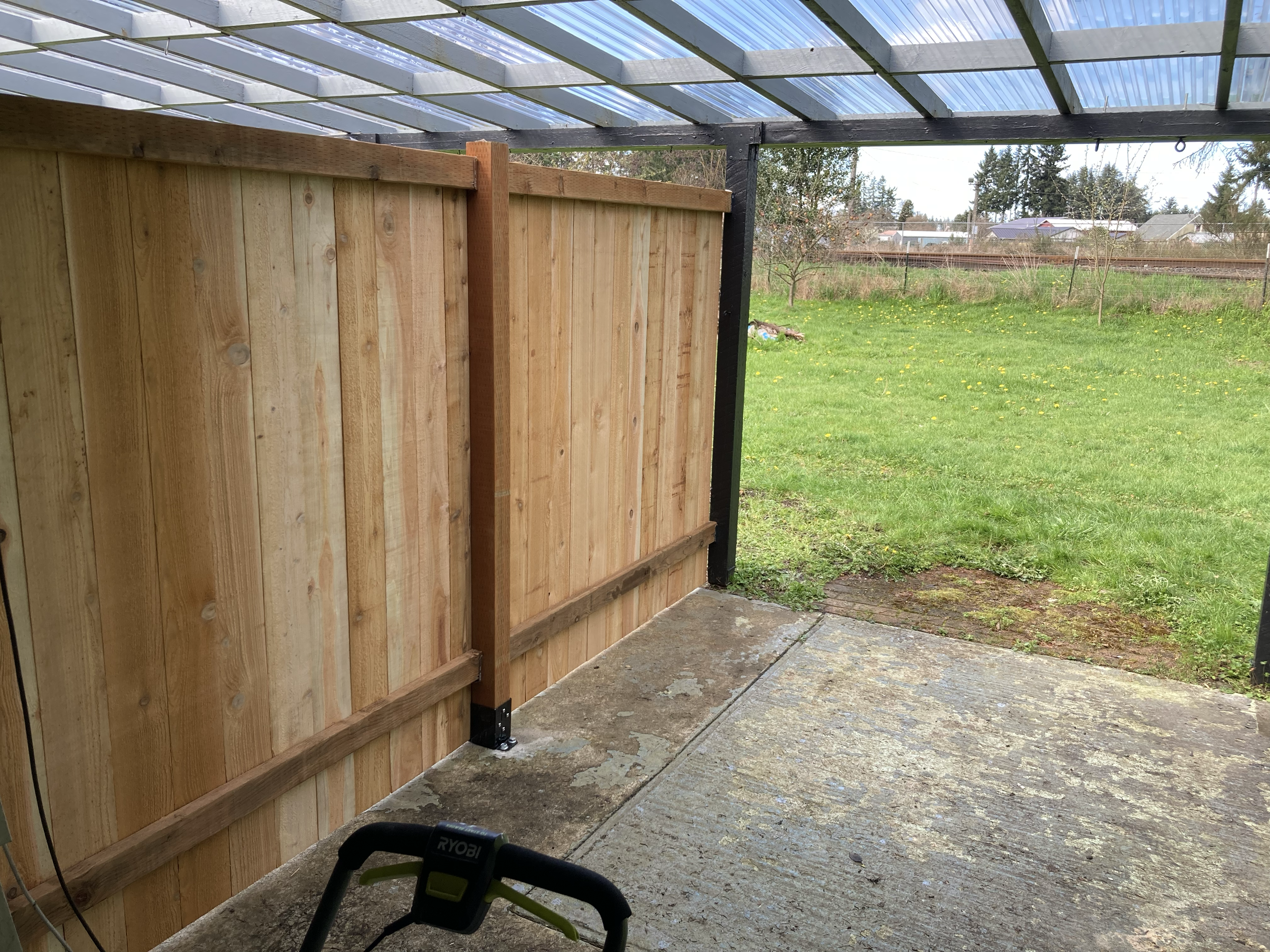Unit C's private backyard — new cedar privacy fence splitting off a covered patio, opening onto the field